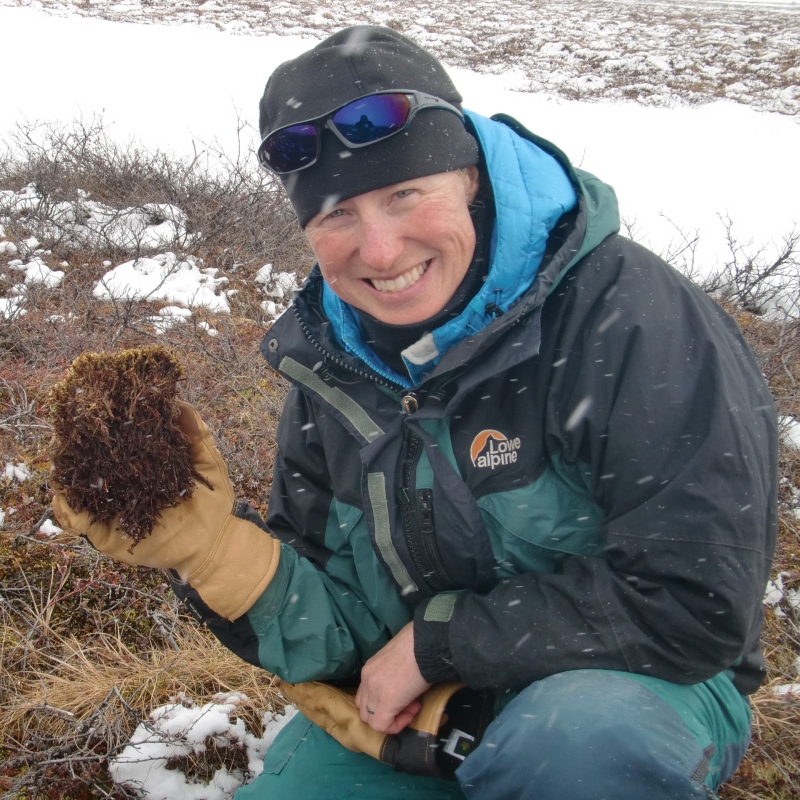 Melissa Barker in the snow holding up soil