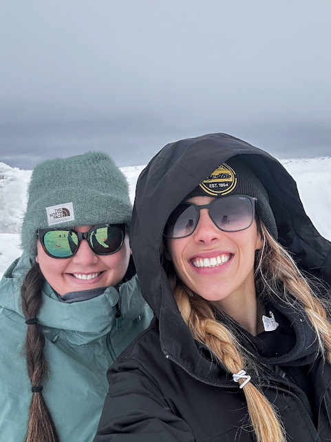 Two women standing in the snow next to each other smiling
