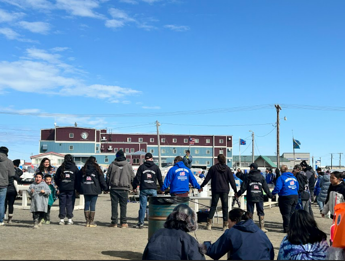 A group of people hold hands in a circle at a festival