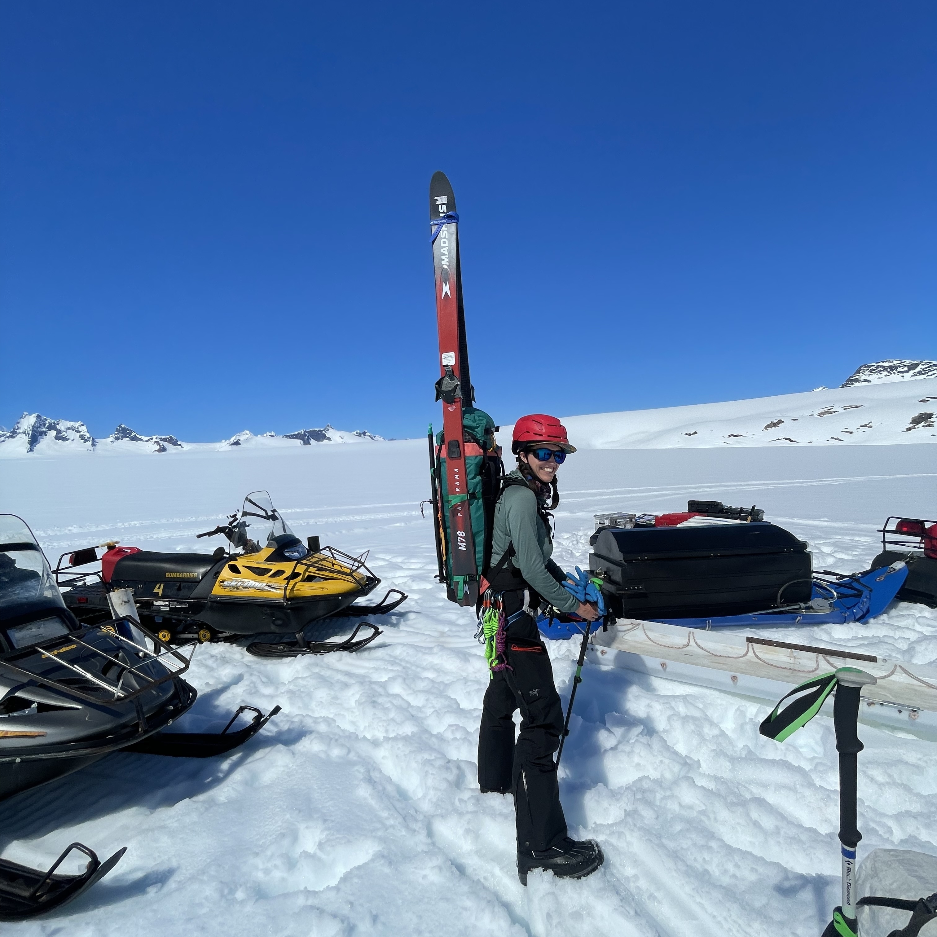 Lynn standing in the snow carrying skis on her back