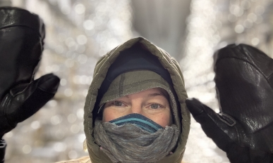 Erika wearing a puffy jacket and holding up her hands in front of shelves of ice cores.