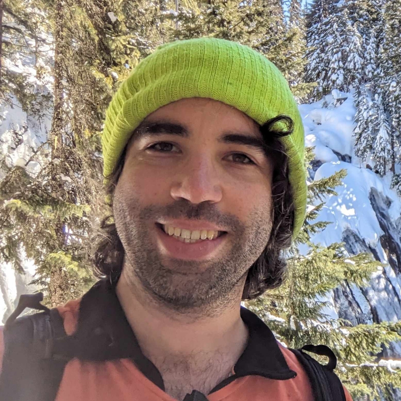 Jesse in front of a snowy mountain and trees