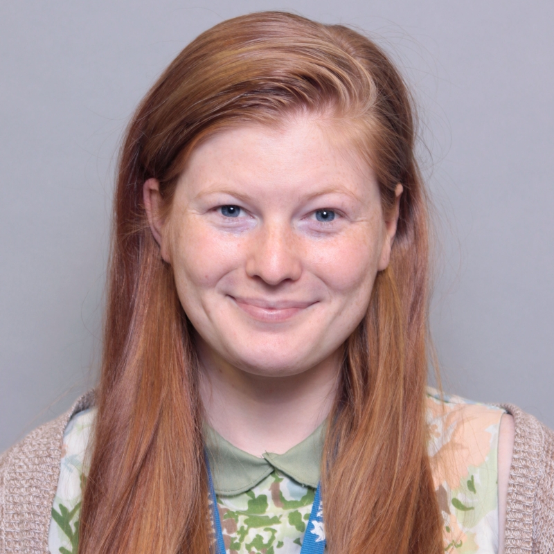 Andi Twiss smiling in front of a gray background