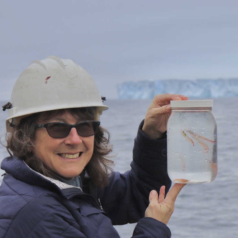 Deborah holds a jar full of water with zooplankton inside.
