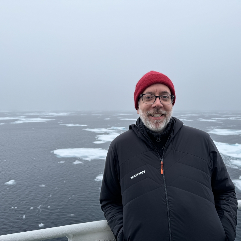 Gabriel standing on the edge of a boat with water and ice behind him