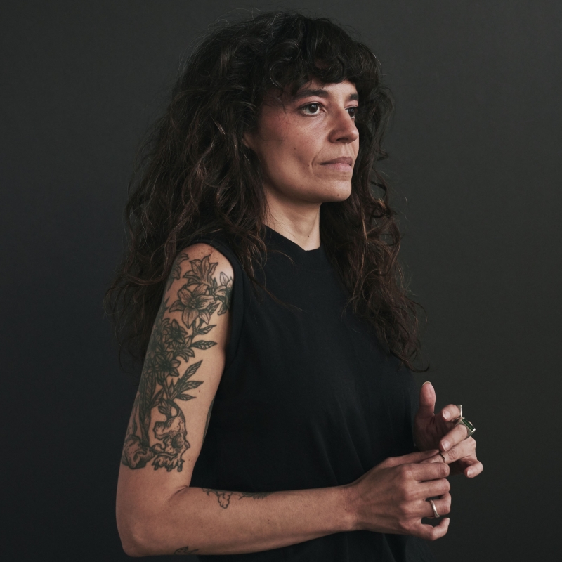 Rebecca looks off to the side in front of a dark gray background