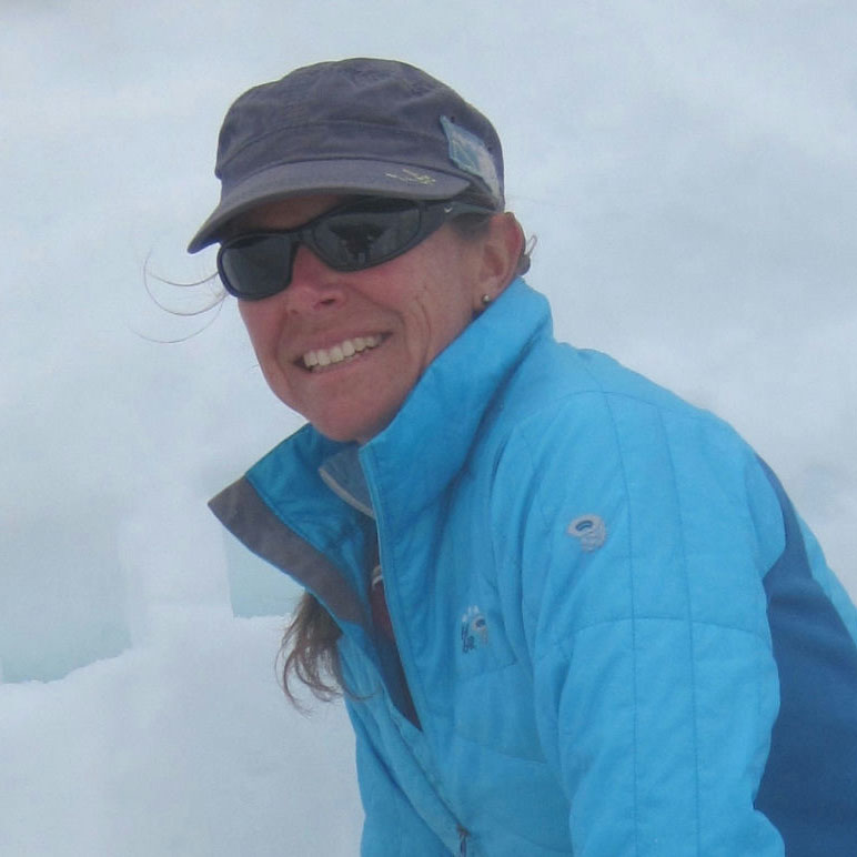 Alison smiling and wearing sunglasses in front of a background of snow.