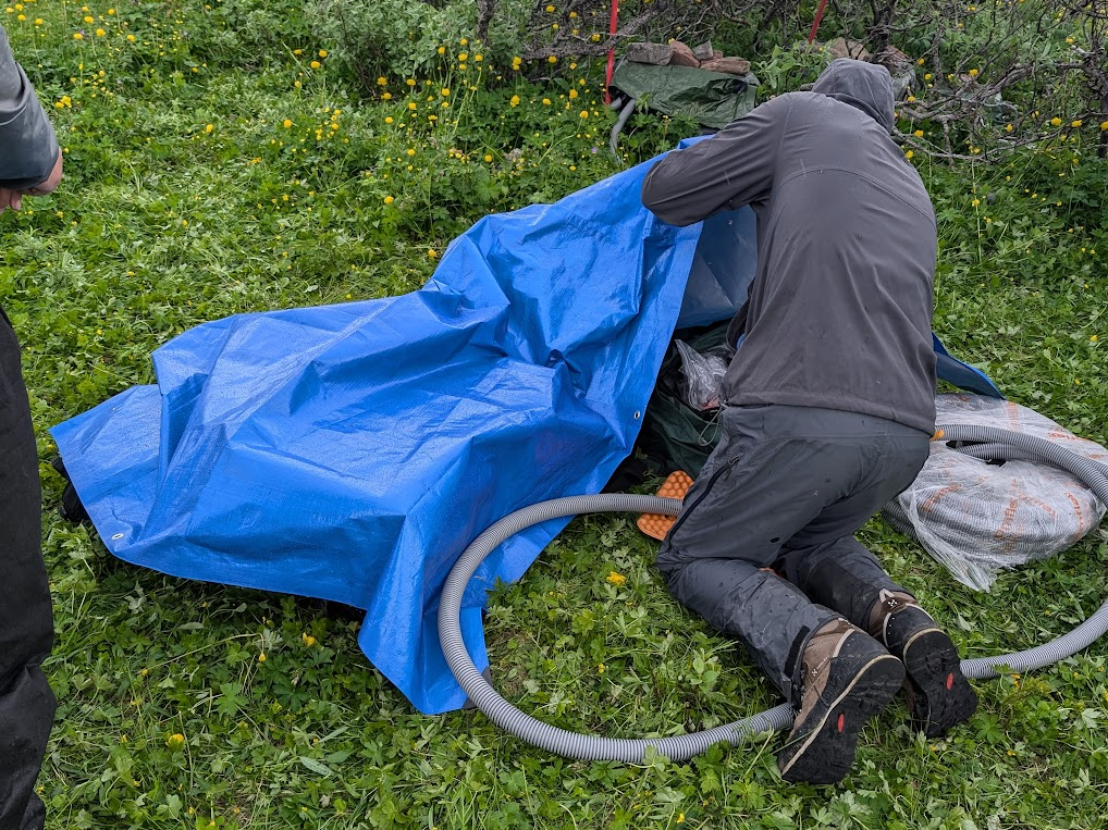 Aleksey covers up scientific equipment with a tarp.