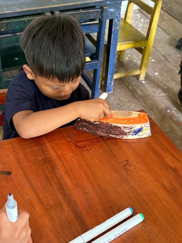A kindergarten student decorates a wooden boat.