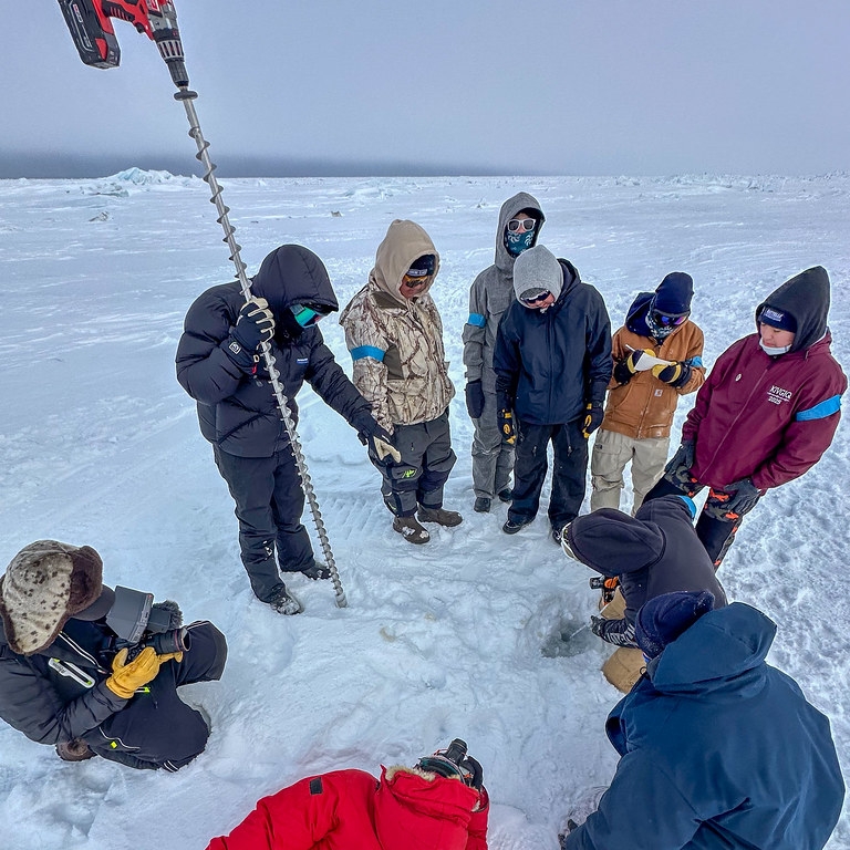 8th grade students using augers to drill holes in the sea ice to assess sea ice depth.