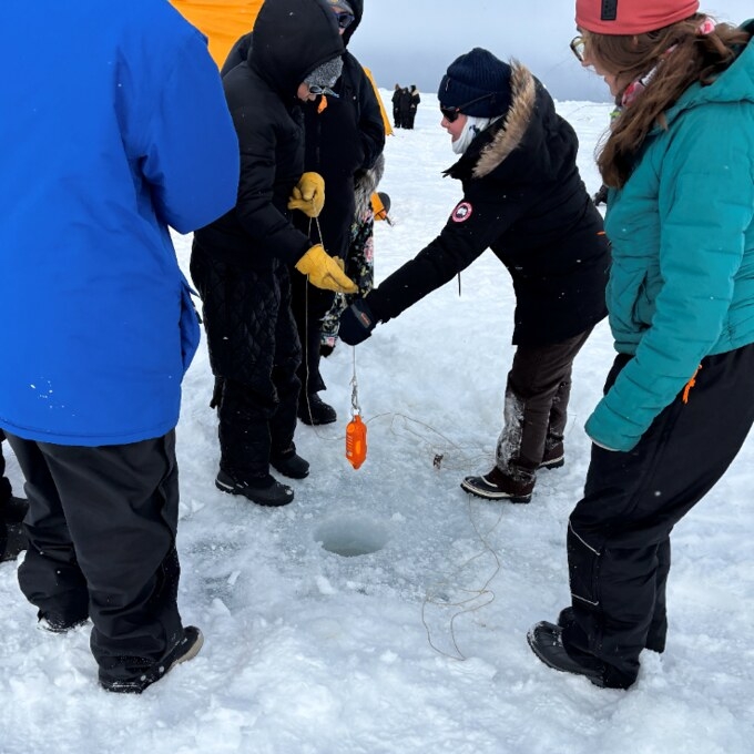 8th graders from Hopson Middle School place a data logger down a hole in the sea ice. Information about water depth and pressure are collected and then analyzed on a computer by scientists.