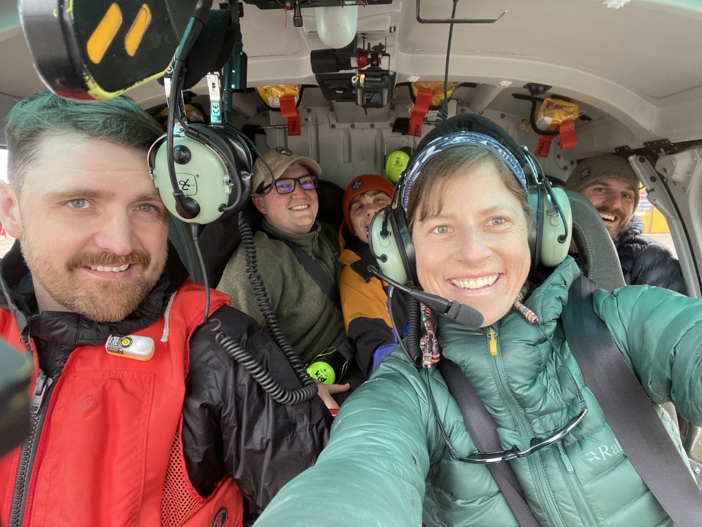 Five people smiling inside a helicopter.
