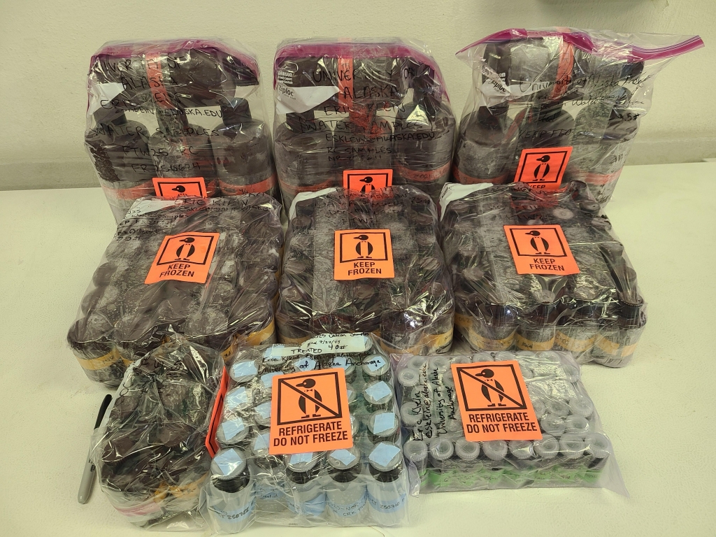 Nine bags of containers of water samples sit on a table