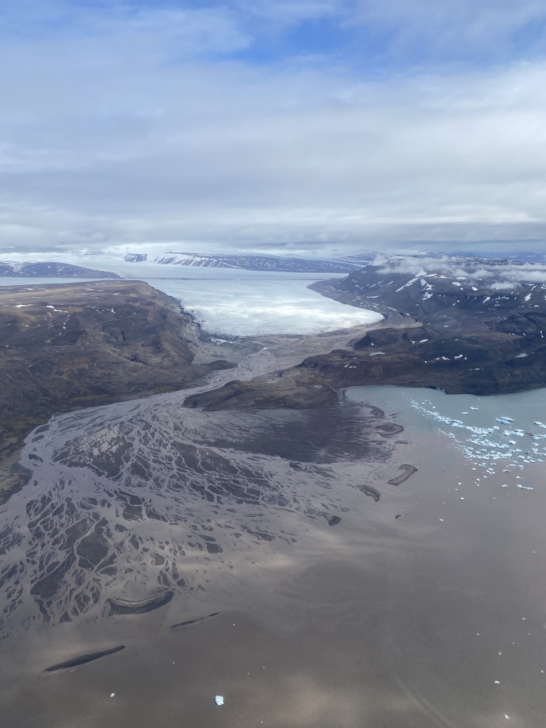 View from above of mountains, snow, and a large body of water