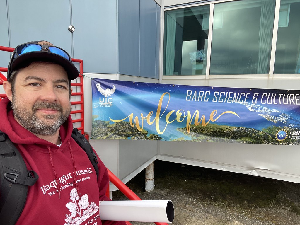 Zachary stands in front of a poster that says "BARC Science & Culture Welcome"
