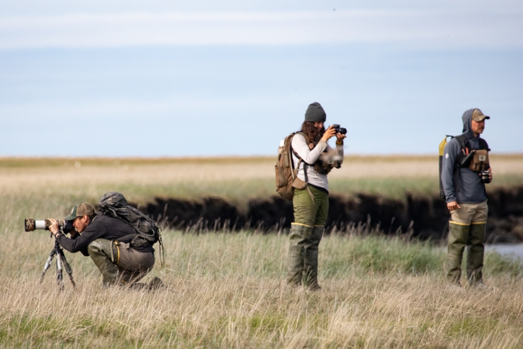 Three people facing different directions while holding cameras