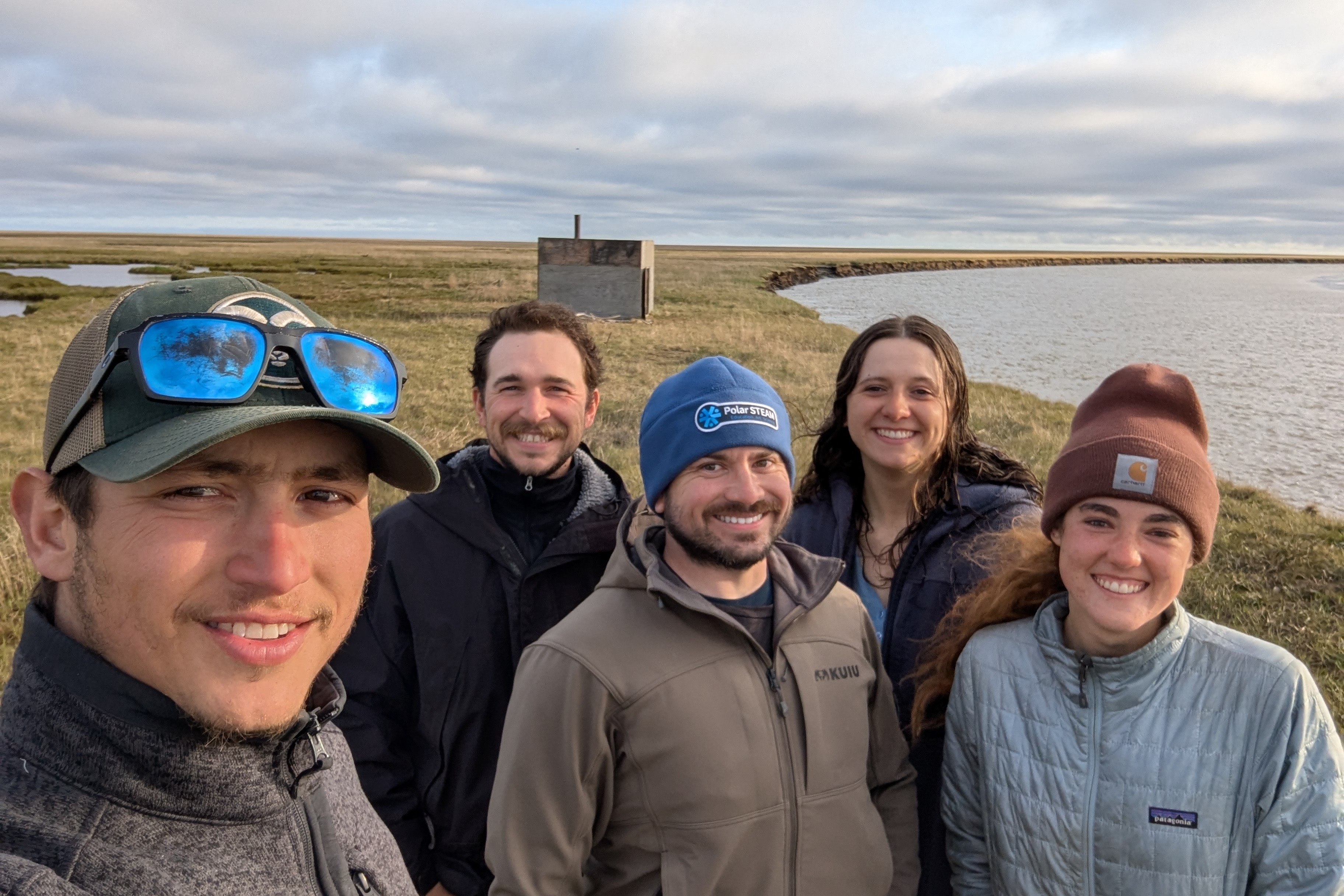 Five people stand smiling looking at the camera with a body