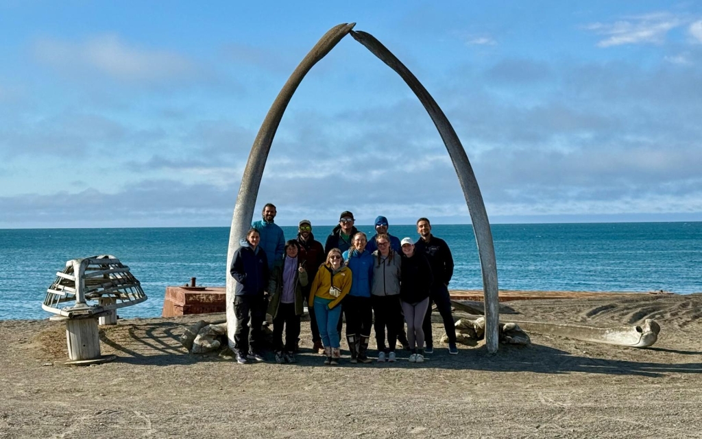 A group of people stands underneath an arch