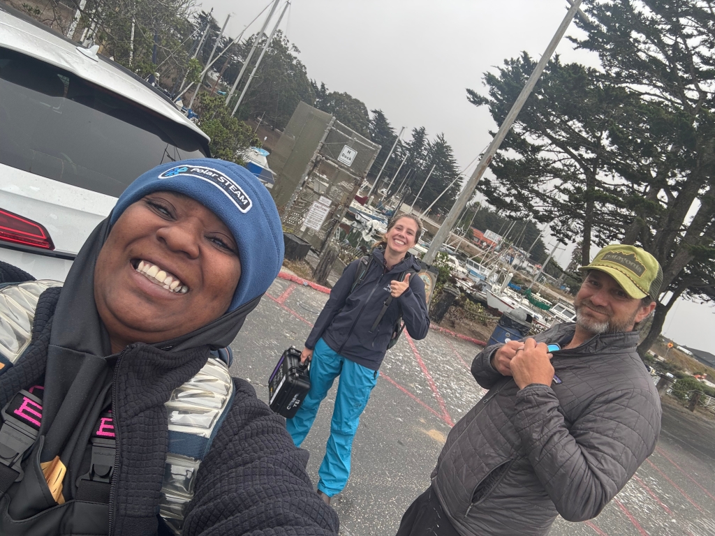 Three people smiling and taking a selfie in a parking lot
