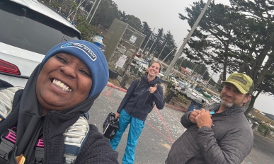 Three people smiling and taking a selfie in a parking lot