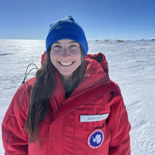 Abby in a bright red snow jacket in front of a snowy background