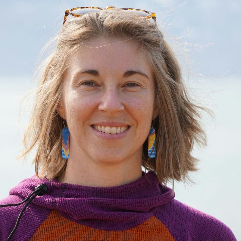 Amanda smiling in front of a blurred blue background