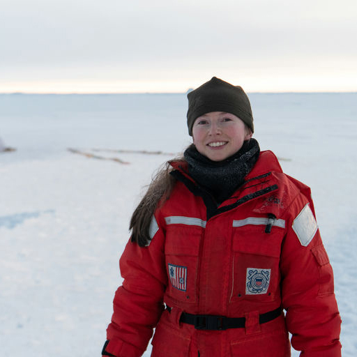 Clare in a bright red snow jacket in front of a snowy background