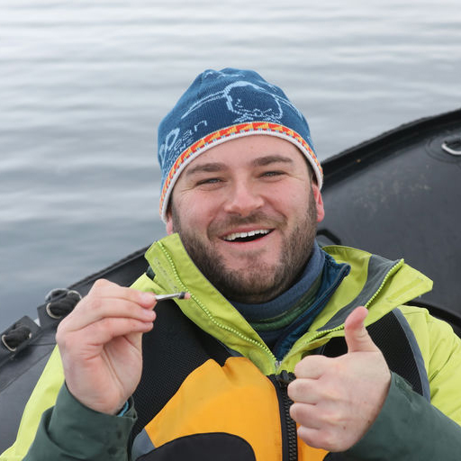 Logan smiling in a boat giving a thumbs up to the camera
