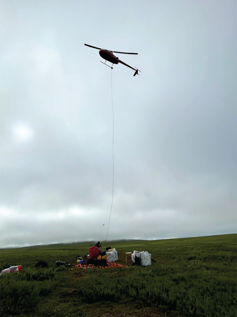 A helicopter up in the air with a rope getting ready to pull something up