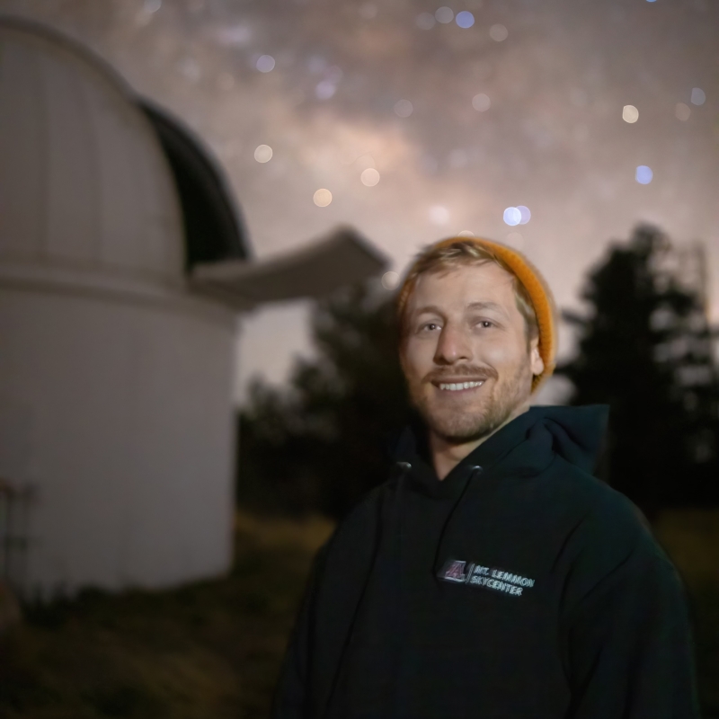 Dave smiling, in the background is an observatory and lots of stars