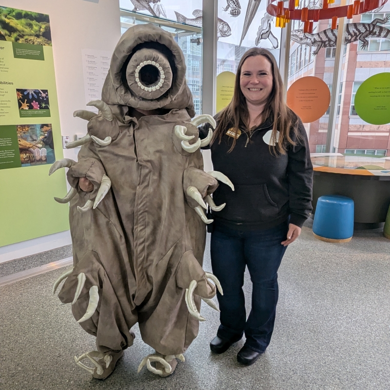 Heather smiling next to a person in a tardigrade costume
