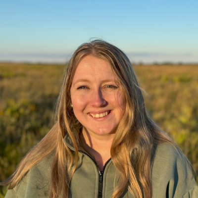 Lacey smiling, background is a field in sunlight