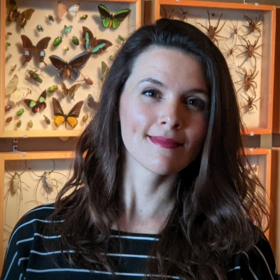 Renae in front of a wall of butterflies and bugs