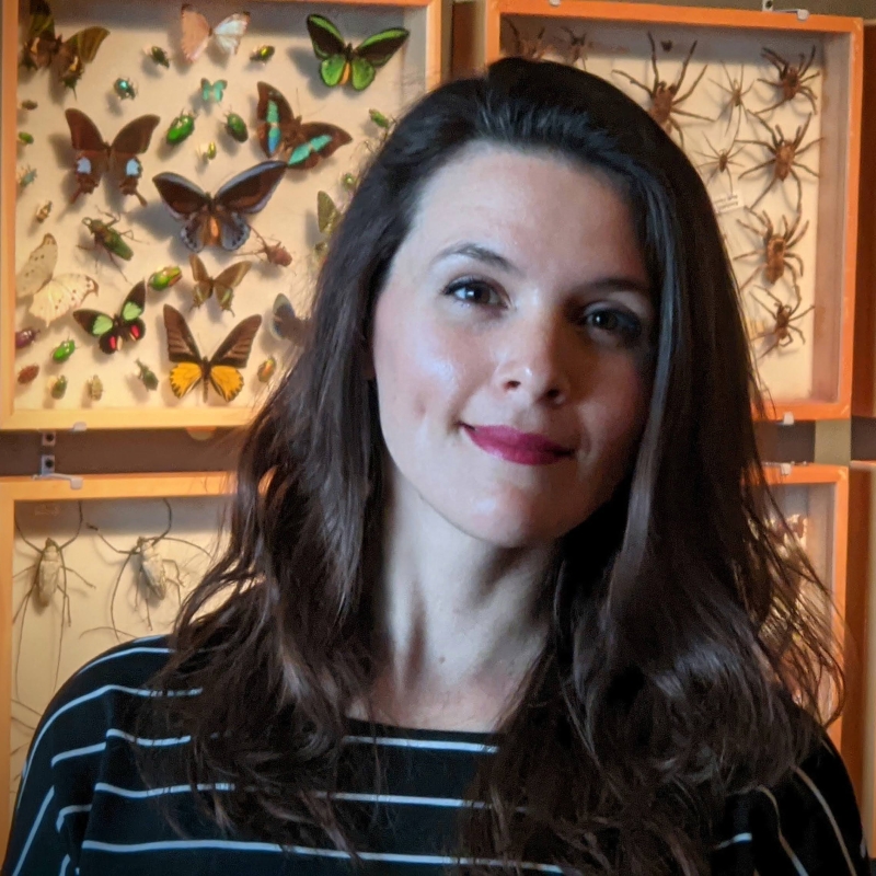 Renae in front of a wall of butterflies and bugs