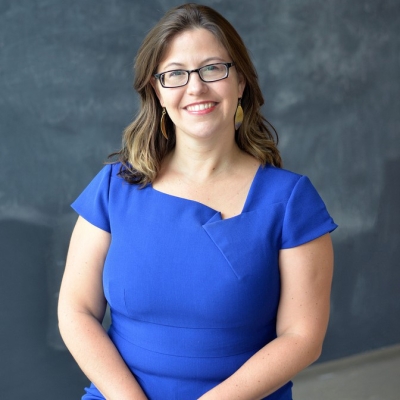Tawny smiling and wearing glasses in front of a black background