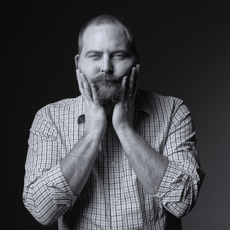 Black and white photo of Tom with his hands on his cheeks