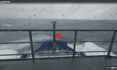 Screenshot still frame of a video showing the bow of a ship with waves with YouTube play icon overlayed.