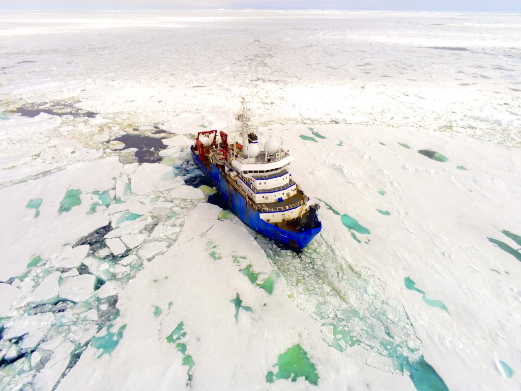 Overhead view of a ship in water surrounded by ice
