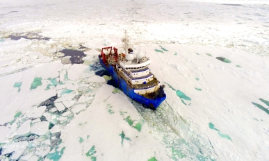 Overhead view of a ship in water surrounded by ice