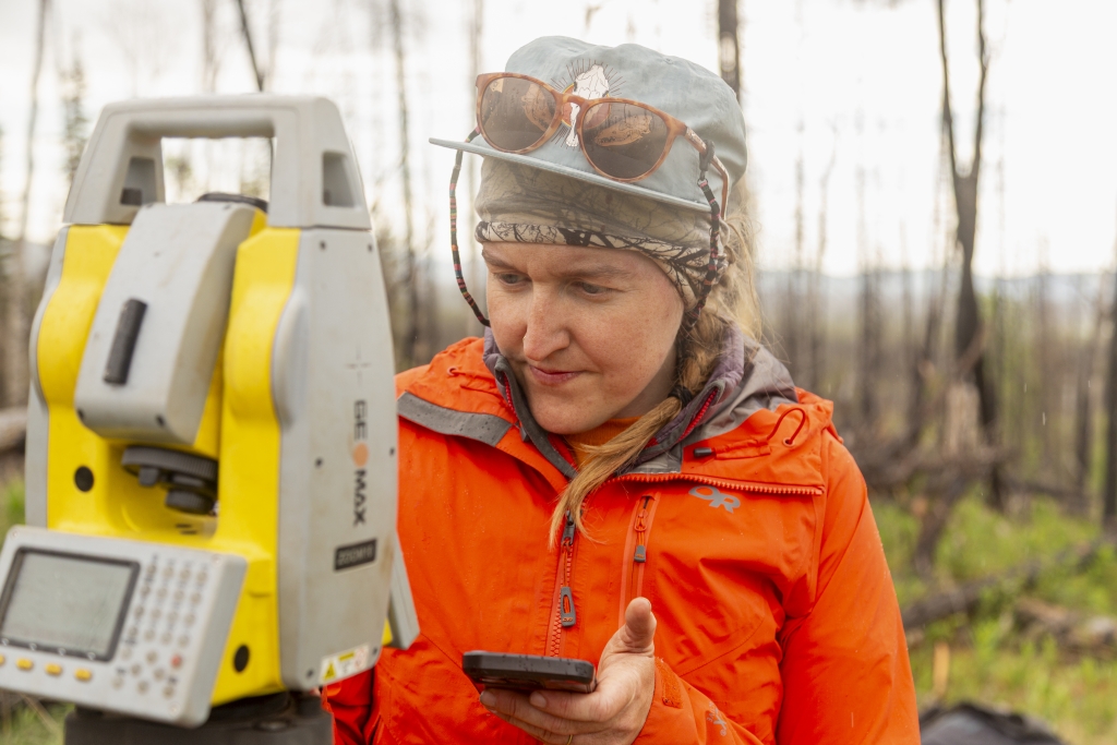 Briana holding a phone and looking at some equipment