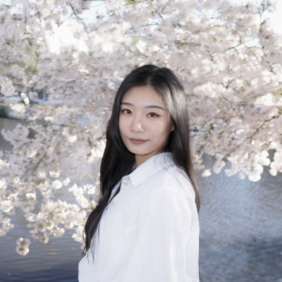 Erica poses in front of a cherry blossom tree with water in the background