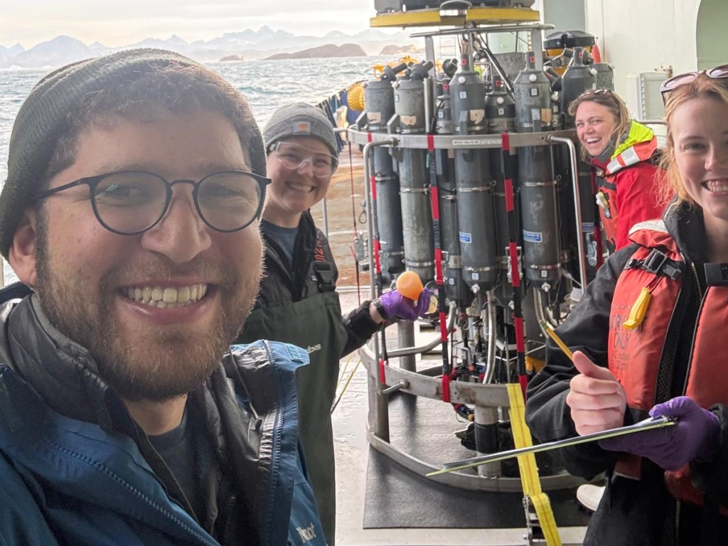 Four people smiling in front of equipment