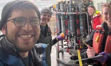 Four people smiling in front of equipment
