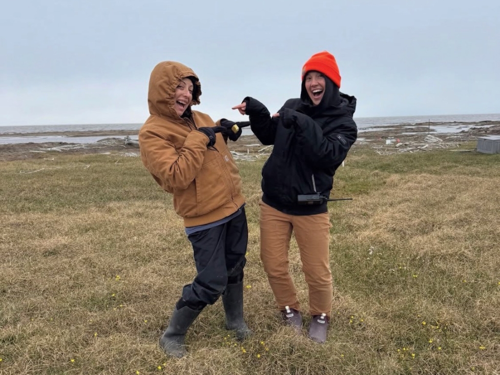 Two people smiling and pointing at each other