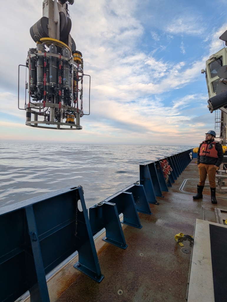 A person standing on a ship looking at equipment about to be lowered in to water