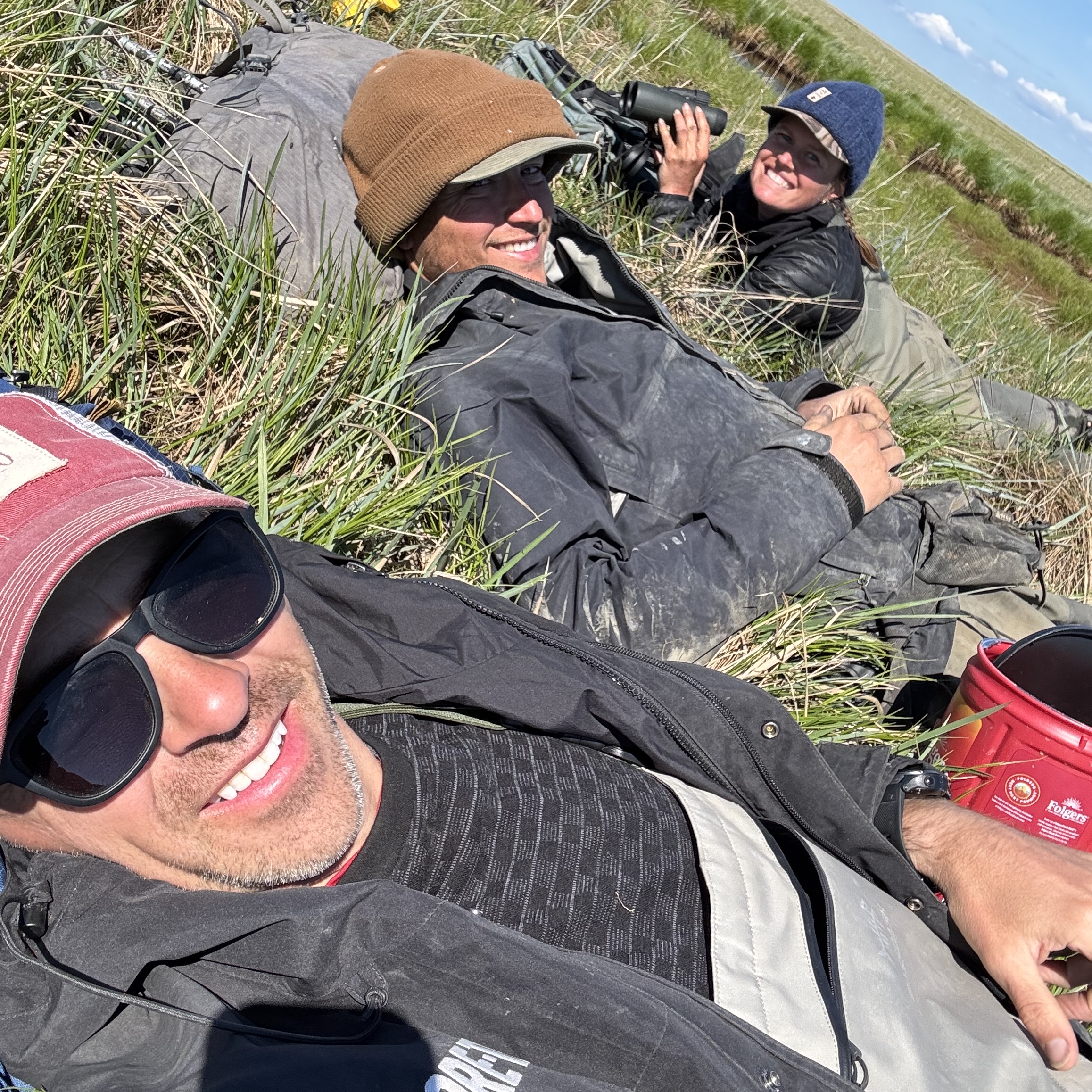 Laying down waiting for the female to return to the nest so that we can spring the trap. Jeff, James, and Mairin.